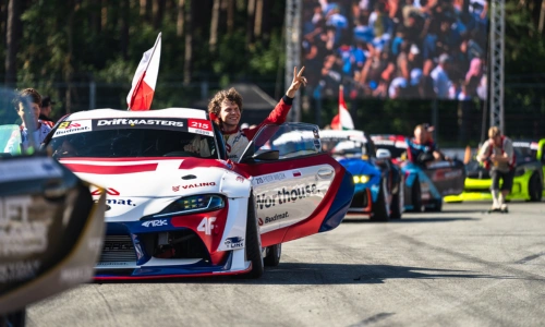 Professional drifter Piotr Więcek standing with Xtreme Clutch sponsored Toyota Supra A90 drift car at racing stadium