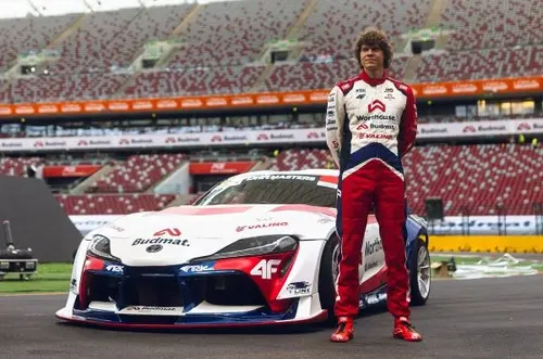 Professional drifter Piotr Więcek standing with Xtreme Clutch sponsored Toyota Supra A90 drift car at racing stadium